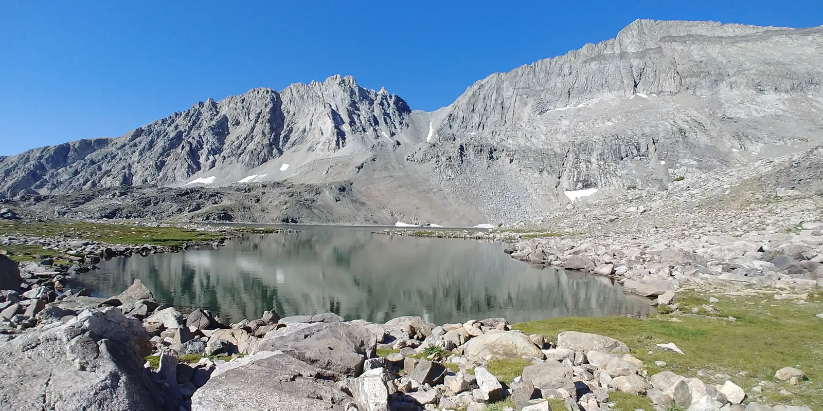 Clear high-country pond reflecting a granite ridgeline in Utah’s Wasatch Back