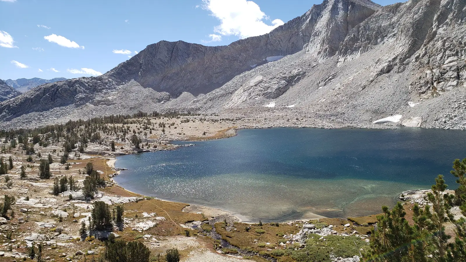 Alpine pond ringed by conifers below granite peaks in Utah’s high country